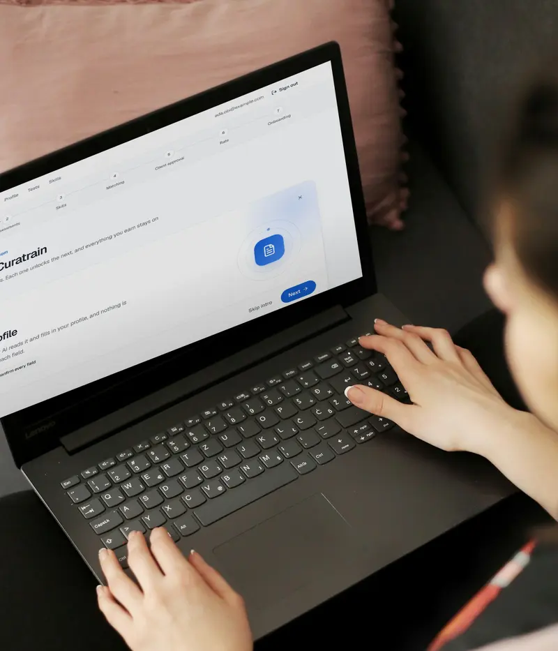 A person typing on a laptop with the Curatrain dashboard open.